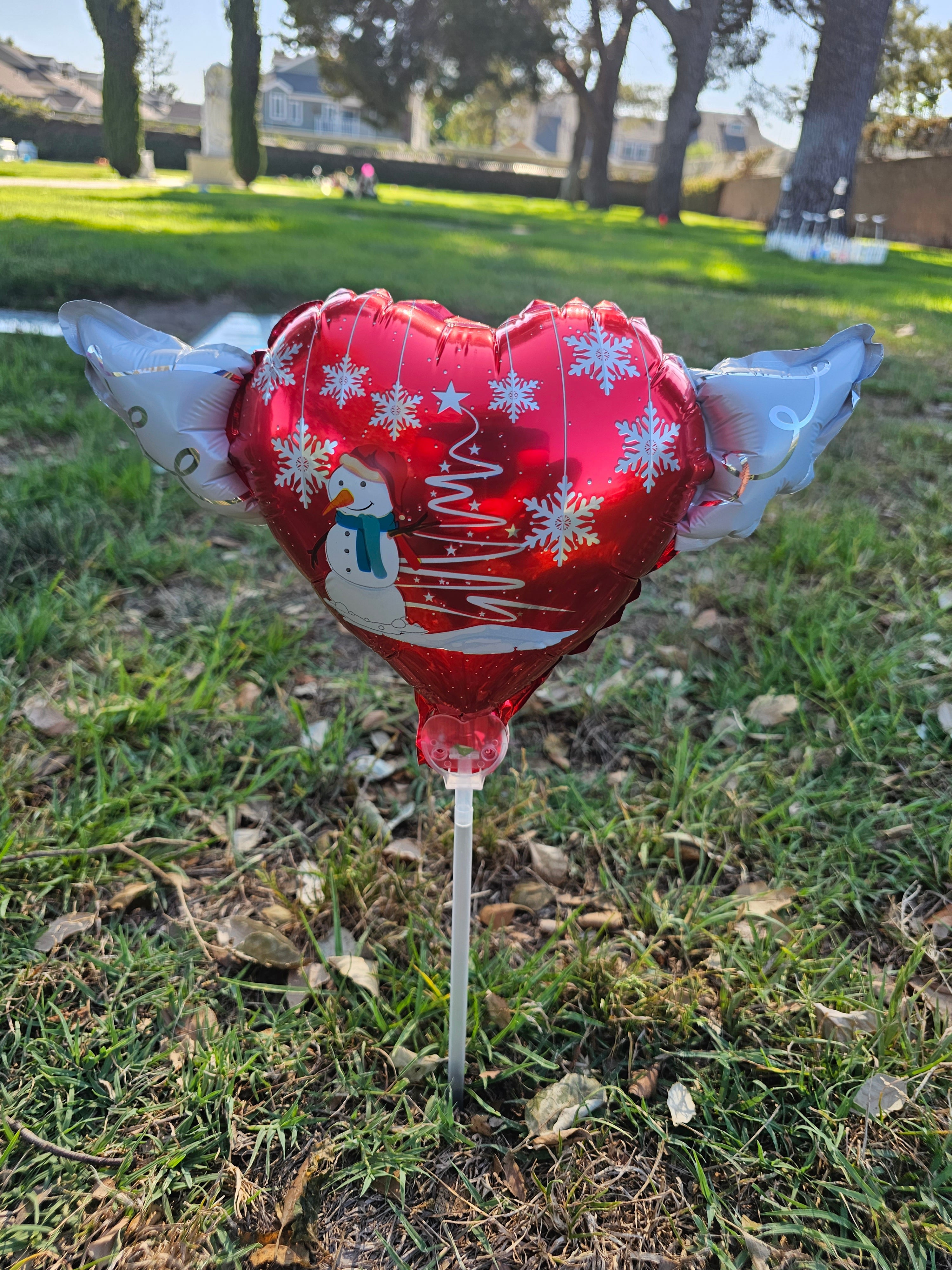 Christmas Snowman Memorial Balloon on a Stick with Angel Wings placed at a cemetery graveside – view 2
