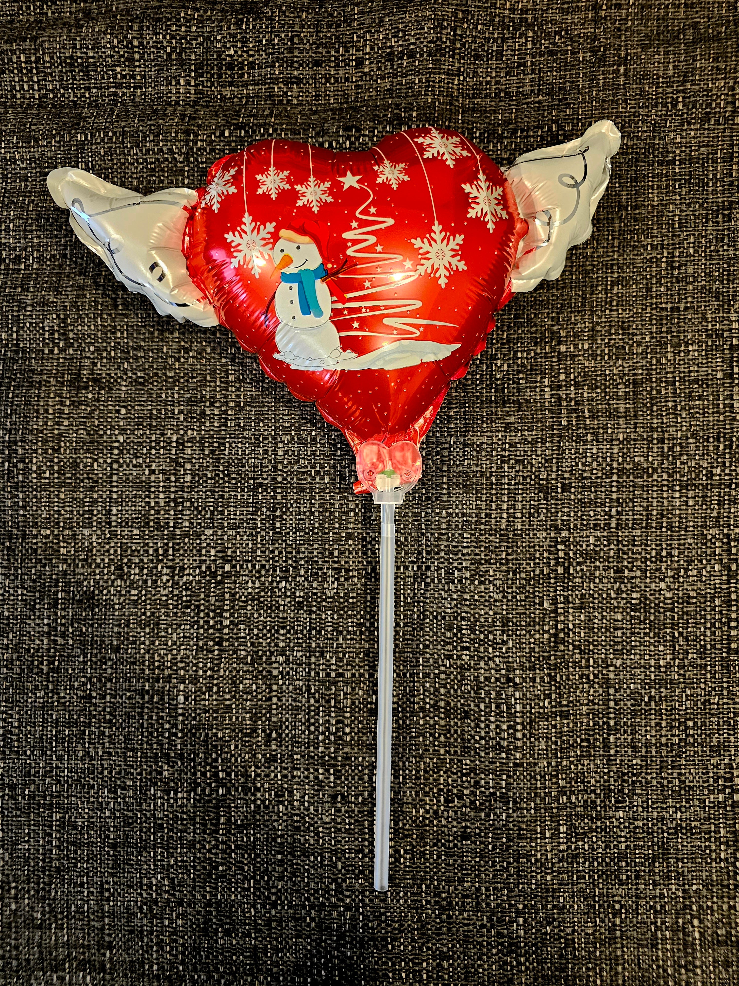 Inflated christmas Snowman Memorial Balloon on a Stick with Angel Wings displayed on a wall