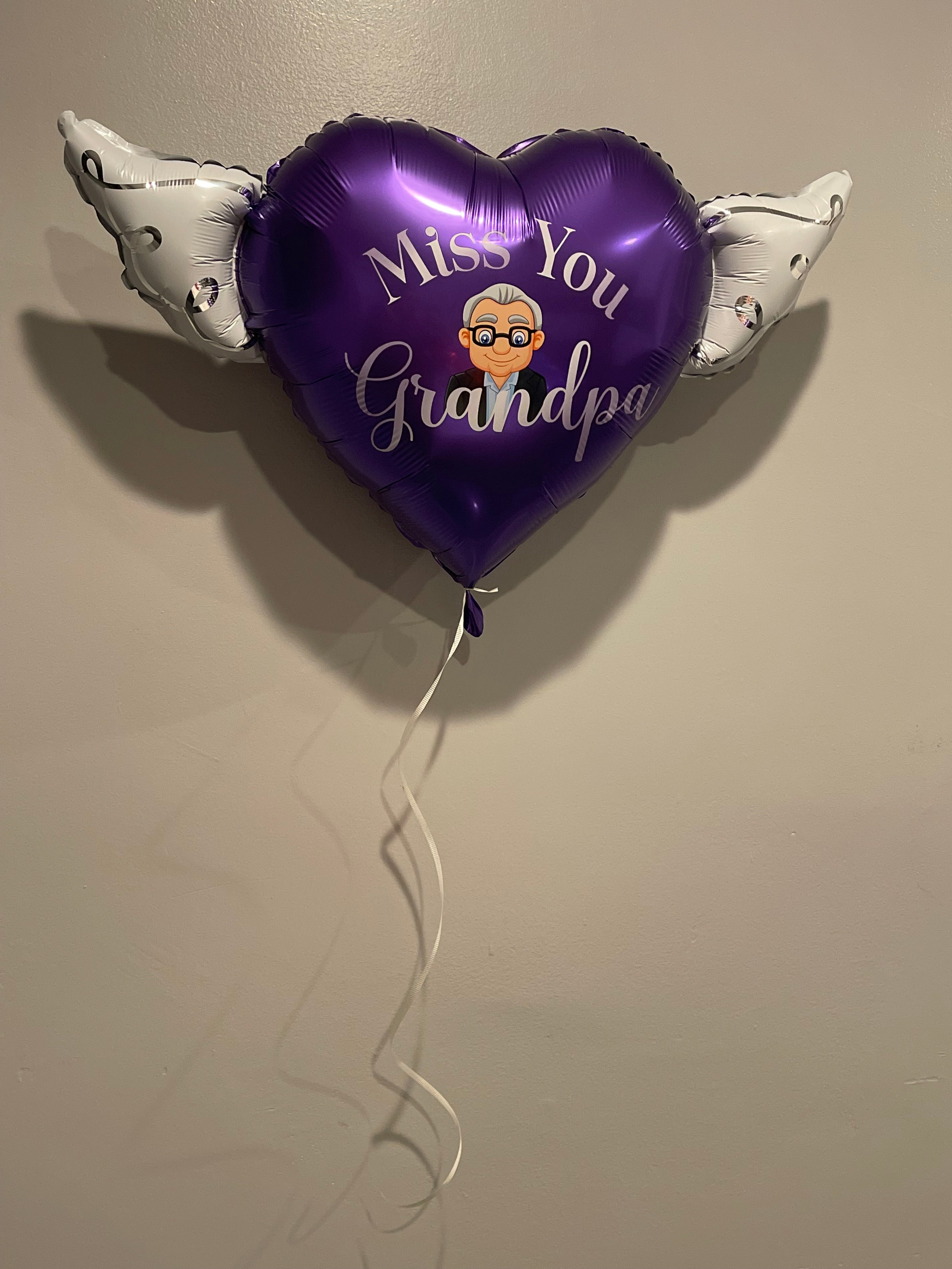 Inflated miss You Grandpa Memorial Balloon displayed on a wall
