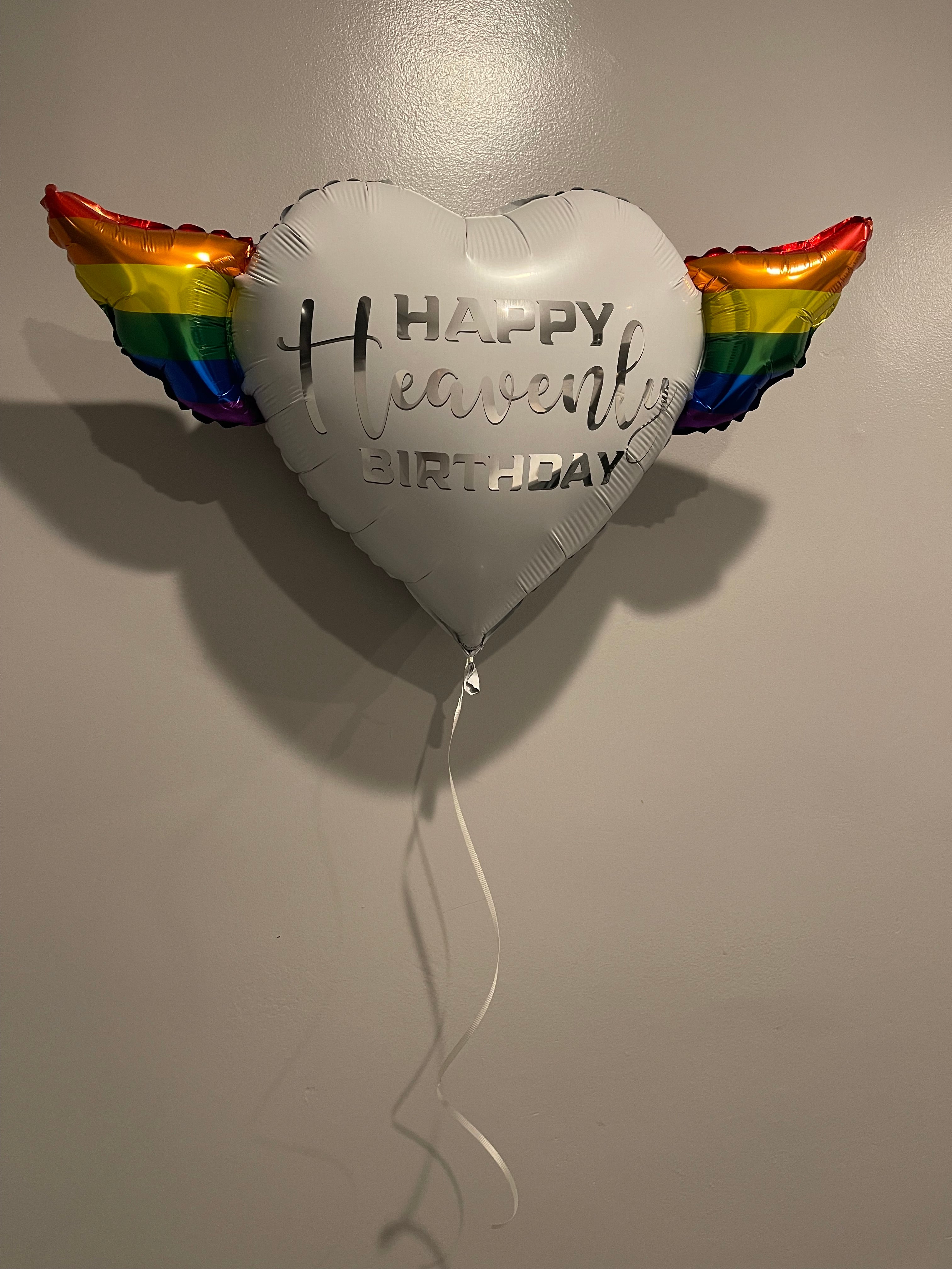 LGBTQ Happy Heavenly Birthday Heart Shaped Balloons with colorful angel wings with the word "Heavenly" in silver